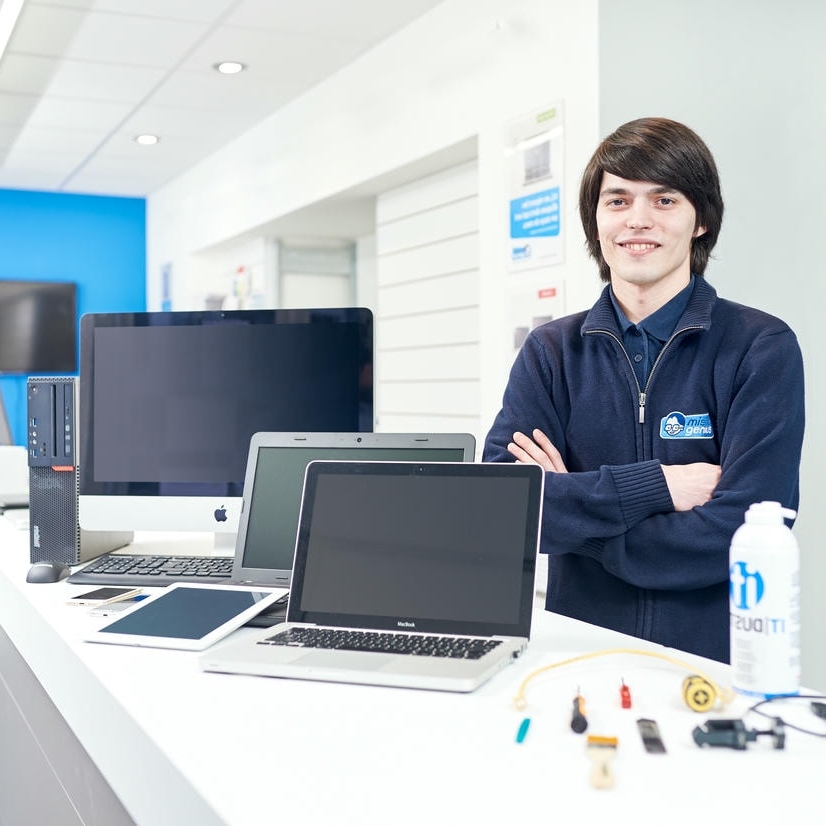 Technicien dépannage informatique avec plusieurs appareils en réparation, incluant ordinateurs portables, PC, tablettes à Bruxelles.