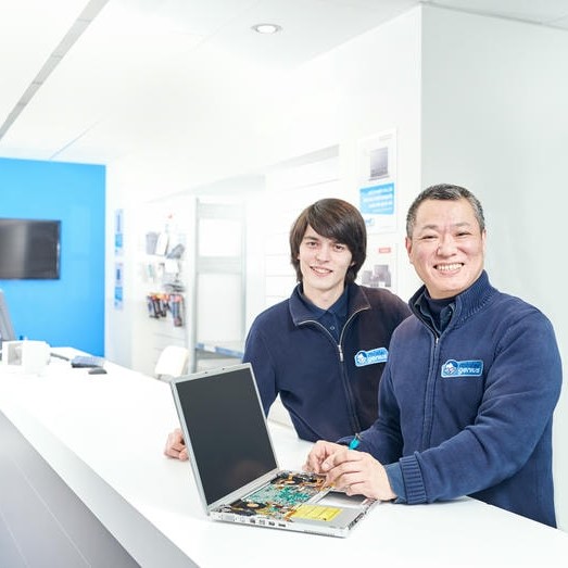 Techniciens Mister Genius réparant un ordinateur portable dans un centre de dépannage informatique à Bruxelles.